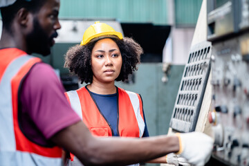 Two African American Mechanical Engineers using a digital tablet and discussing workshop machine maintenance in a factory, exam, inspection, training, Working together, teamwork concept.