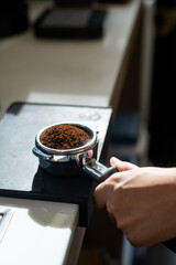 Barista preparing coffee in a coffee machine, close-up.