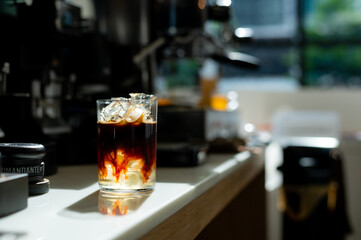 Coffee in a glass with ice cubes on the bar counter