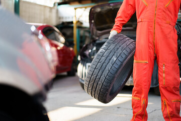 Portrait of professional Asian male vehicle technician or repairman in orange suit holding -...
