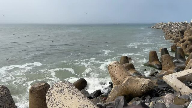 Ships on a foggy horizon with dolosse along the shoreline