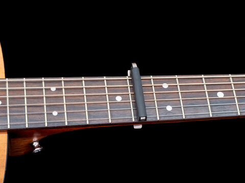 Capo on the Acoustic guitar neck , capro made from aluminium, Selective focus at capo.