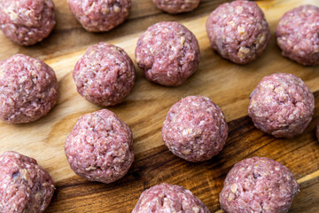 Raw, homemade, and handrolled Swedish metaballs on a kitchen counter ready to be fried.