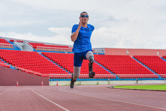 Asian male athlete with prosthetics runs at full speed, demonstrating a powerful practice on stadium track