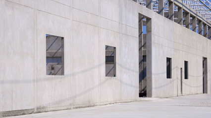 Perspective side view of concrete wall structure with roof beam of incomplete factory building in construction site