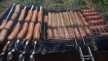Cooking delicious and juicy sausages on the grill close-up. Roasted sausages on fire with smoke. Coocking hot food in nature on the weekend