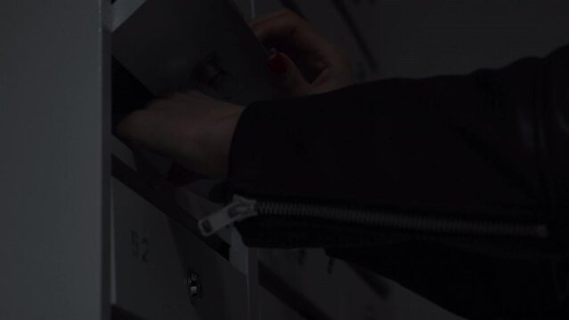 Close up of metal new mailboxes in the house entrance. Concept. Woman hands taking letter from the mailbox.