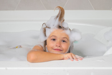 Kids shampoo. Little child in a bath tub. Washing in bath. Kid with soap suds on hair taking bath. Closeup portrait of smiling kid, health care and kids hygiene. Kids face in bath tub with foam. - obrazy, fototapety, plakaty