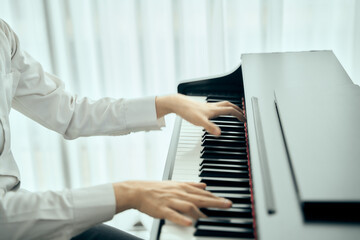 A man pianist wearing white suit and black plant perform piano classical song in close up shot with...