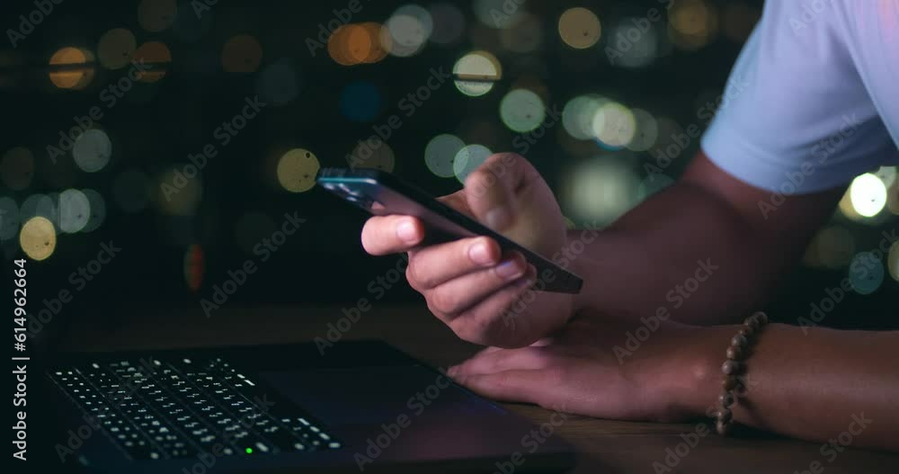Wall mural close-up of business man writing a message on a mobile phone while working on a laptop on background
