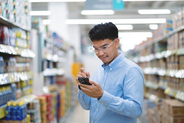 Asian young man choosing in supermarket Male customers standing in the grocery store. Salesperson or store manager in a supermarket.