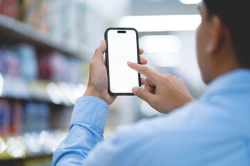 Asian man holding smartphone in hand with white mockup screen template. Mobile app advertising concept. shopping and checking prices in a shopping mall.