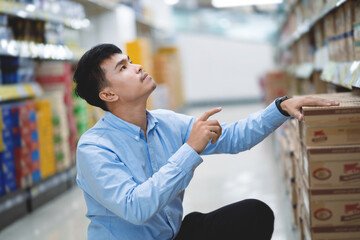 Portrait of a handsome Asian male salesman in a supermarket. Men in the grocery store. Small business. Smiling man in a shop.