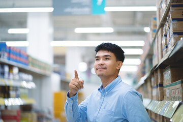 Happy Asian man in blue shirt Check products in supermarket warehouse inventory. Import and export business.