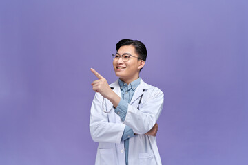 A portrait of a happy male doctor pointing at a copy space.