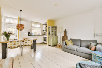 a living room with white wood flooring and yellow painted walls in the background, there is a grey couch