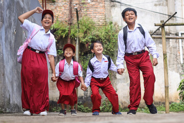 Attractive elementary school kids wearing school uniform, jumping together. 