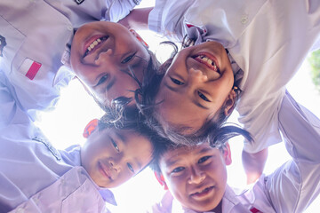 Close up face of happy smiling kids embracing together in a circle and looking at camera