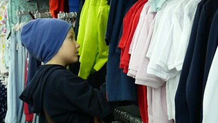 A child chooses clothes hanging in a row in a clothing store