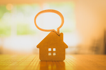Model wooden house with dialogue bubble on wooden table. Home communication concept. Problems in...