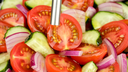 Pouring olive oil on fresh vegetable salad. Mediterranean cuisine