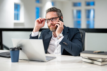 Business man talking on phone at office workplace. Gray hair mature business man director using laptop. Millennial manager at office workplace. Ceo office workers business people at office.