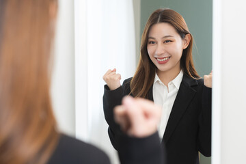 Confident, cheer up asian young woman standing in suit formal, smiling look in reflection mirror at...