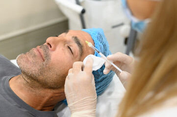 Adult man undergoing skin lifting procedure at clinic