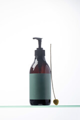 A mock-up of a brown dispenser with cosmetics with a place for your logo on a glass shelf. Natural cosmetics.