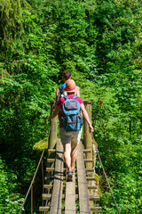 Wanderer beim überqueren eines Fußgängerstegs über einen kleinen Fluss