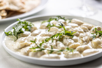 Gnocchi ai quattro formaggi, Italian dough pasta with four types of cheese and ruccola on top
