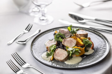 Baked pork with carrots, puree and dressing piled and decorated on a plate in the restaurant