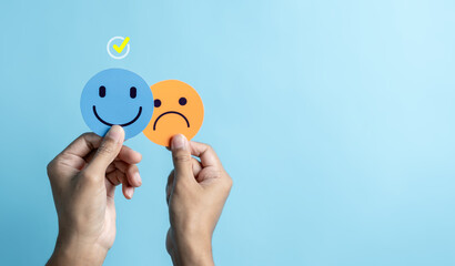 Hands holding sad face hiding or behind happy smiley face, bipolar and depression, mental health...