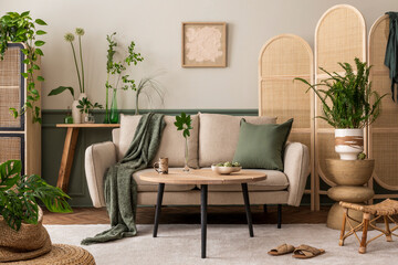Interior design of spring living room interior with mock up poster frame, beige sofa, wooden coffee table, plants in flowerpots, rattan sideboard and personal accessories. Home decor. Template.