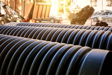 Close-up of large plastic corrugated pipes for water supply against the background of construction...