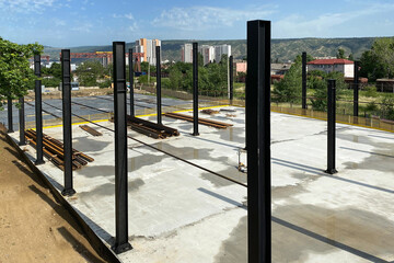 Preparation of concrete foundation and steel construction piles on background sky.