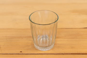 Glass empty on wooden table closeup with selective focus.