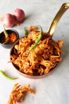 Fried onion pakode or Pyaj ke Pakore also known as Crispy Kanda bhaji, Bhajji, bujji. favorite Indian Tea-Time snack during the monsoon. served with fried green chili and red garlic chutney.copy space