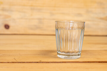 Glass of water on a wooden table with selective focus and copy space