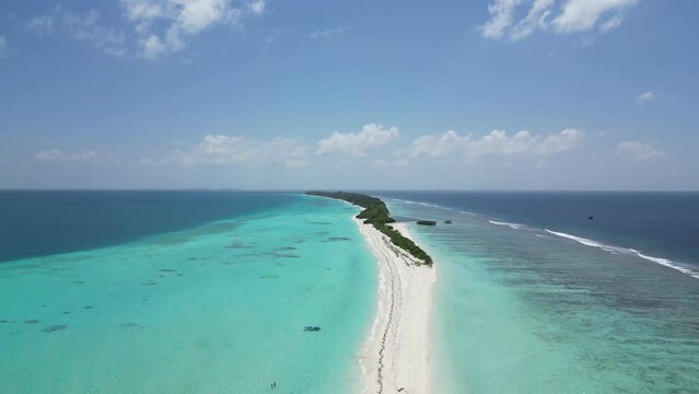 Vast shallow lagoon of turquoise blue clear water surrounding long white sandbar of Dhigurah Island, Maldives. Aerial dolly in