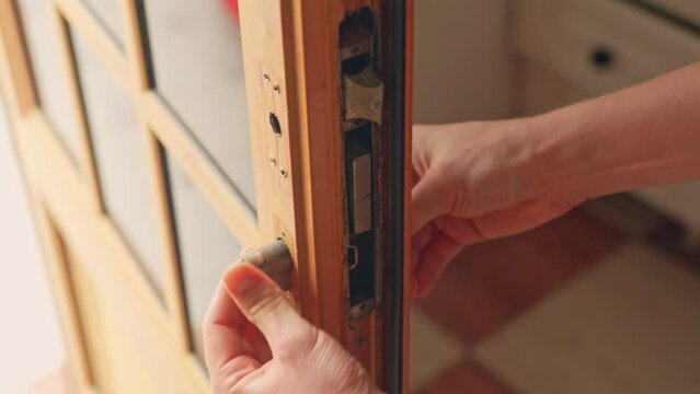 Close up of hands repairing broken door lock, disassembling locking parts