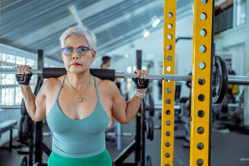 Fototapeta na wymiar Senior woman doing exercises in the gym to stay healthy, trains muscles.