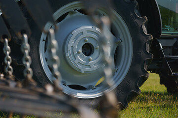 Red tractor with tooth harrow in the green field in Ukraine