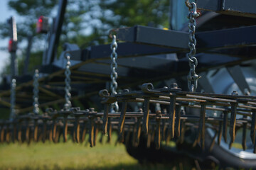 Red tractor with tooth harrow in the green field in Ukraine