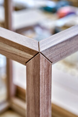 Wooden frame of bedside table made of solid walnut in workshop. Joinery angular joint of planks on...