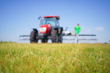 Red tractor with tooth harrow in the green field in Ukraine