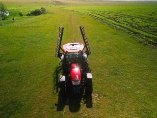 Red tractor with tooth harrow in the green field in Ukraine