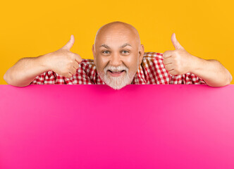 cheerful senior man with copy space on blank banner. advertisement. thumb up