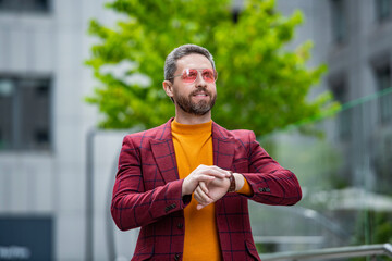 punctual man check time in the street. punctual man check time outside. punctual man check time on watch. punctual man in jacket check time outdoor