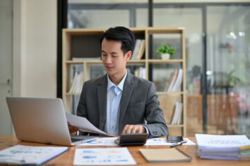 Fototapeta na wymiar A professional Asian businessman focuses on business financial reports, working at his desk